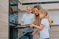 Mom teaches her daughters to cook in the kitchen. The family bakes cookies in the oven