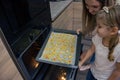 Mom teaches her daughters to cook in the kitchen. The family bakes cookies in the oven