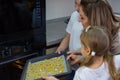 Mom teaches her daughters to cook in the kitchen. The family bakes cookies in the oven