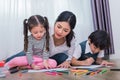 Mom teaching children in drawing class. Daughter and son painting with colorful crayon color in home. Teacher training students in