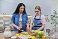 Mom and teen daughter cooking apple pie together at home kitchen Royalty Free Stock Photo