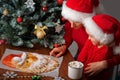 Mom tells her daughter a story about Santa next to a Christmas tree and a cake in the form of Santa Claus