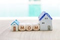 Mom text on wooden cube with miniature house over blurred background Royalty Free Stock Photo