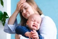 Mom tired trying to calm her crying baby. Newborn tantrum child on mother hands. Family life, motherhood