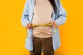 Mom-to-be& x27;s progress. Pregnant woman measuring her belly with tape, standing on yellow background, cropped, closeup Royalty Free Stock Photo