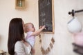 Mom and Toddler Daughter playing menu planning write to blackboard and chalk, Royalty Free Stock Photo