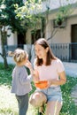 Mom treats little girl with strawberries while squatting with a bowl in the garden