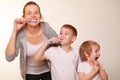 Mom and two blond boys brush their teeth