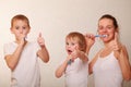mom and two blond boys brush their teeth