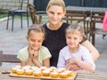 Mom and two daughters sitting at table on which lay cooked them Easter cupcakes Royalty Free Stock Photo