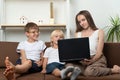 Mom with two sons are looking at laptop screen. Doing homework with children. Homeschooling Royalty Free Stock Photo