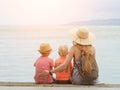 Mom and two sons sit on the pier and admire the sea and the moun Royalty Free Stock Photo