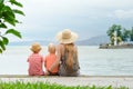 Mom and two sons sit on the pier and admire the sea and the mountains in the distance. Back view Royalty Free Stock Photo