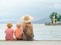 Mom and two sons sit on the pier and admire the sea and the mountains in the distance. Back view Royalty Free Stock Photo