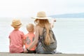 Mom and two sons sit on the pier and admire the sea and the mountains in the distance. Back view Royalty Free Stock Photo