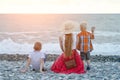 Mom and two sons sitting on the beach and watching the waves. View from the back Royalty Free Stock Photo