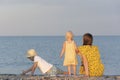 Mom with two young children sitting on the beach. Back view. Summer holidays with children Royalty Free Stock Photo