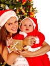 Mom wearing Santa hat holding baby under Christmas tree. Royalty Free Stock Photo