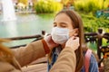 Mom wears a protective disposable face mask to her daughter.