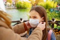 Mom wears a protective disposable face mask to her daughter.