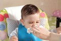 Mom wipes the son drool with a napkin. Baby care, Mother Wipes Baby Mouth With Napkin After Feeding