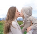 Mom woman autumn park kisses child, little boy son 3-5 years old, nature, relax on walk, in spring city, green grass Royalty Free Stock Photo