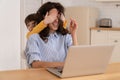 Mom work on laptop at home during lockdown, child distracts from work, covering her mother's eyes. Royalty Free Stock Photo