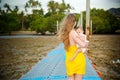 Mom in a yellow dress with a one year old baby walk on a pantone pier at low tide Royalty Free Stock Photo