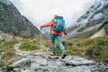 Moman with backpack and trekking poles crossing mountain creek during Makalu Barun National Park trek in Nepal. Mountain hiking