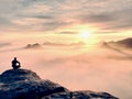 Moment of loneliness on exposed rocky summit. Man in black enjoy marvelous view. Hiker sit on the peak