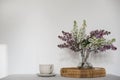 Moment of tranquility with cup of coffee, wicker tray. Floral bouquet of blooming purple and white lilacs branches in Royalty Free Stock Photo