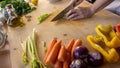 Moments of daily life in the Mediterranean cookery: low angle view of a young female cook cutting celery with various vegetables