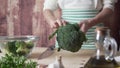 Moments of daily life in Mediterranean cuisine: a young cook cleans a broccoli from the external leaves with a bokeh effect in the