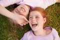 Moments with my sister. Two little girl lying happily on the grass and laughing. Royalty Free Stock Photo