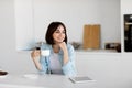 Moments of relax. Dreamy lady drinking coffee and looking away, sitting in kitchen interior, free space