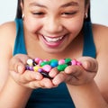 Moments before the sugar rush. Studio shot of a cute young girl holding a handful of colorful jelly beans.