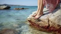 Moments of Tranquility. A Young Woman\'s Feet Finding Solace on a Stone Beach, Overlooking the Mesmerizing Turquoise Expanse.