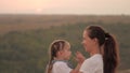 Mommy and baby hug. Mom plays with her daughter and shows child sunset. Happy family, mom and daughter in field look at Royalty Free Stock Photo