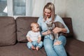 Mommy, daughter and cat sits on the couch in the home interior