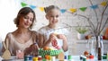 Mommy and daughter decorating branches with hand-made toys, Easter traditions