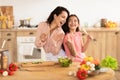 Mommy and daughter singing in kitchen enjoying cooking fun