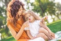 Mommy feeding her girl with grapes in the park at daytime