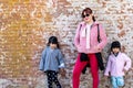 Mommy and her identical twins happy pose with old brick wall background Royalty Free Stock Photo