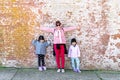 Mommy and her identical twins happy pose with old brick wall background Royalty Free Stock Photo