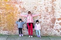 Mommy and her identical twins happy pose with old brick wall background Royalty Free Stock Photo