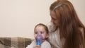 Mommy inhales a little girl in a mask with a nebulizer at home. The child is receiving respiratory therapy with a Royalty Free Stock Photo