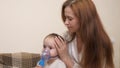 Mommy inhales a little girl in a mask with a nebulizer at home. The child is receiving respiratory therapy with a Royalty Free Stock Photo