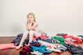 Mommy little helper. Bored Caucasian girl sorting clothes. Tired funny child arranging organazing clothing. Kid with messy stack