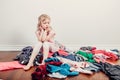 Mommy little helper. Bored Caucasian girl sorting clothes. Tired funny child arranging organazing clothing. Kid with messy stack