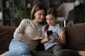 Interested mom watch tween daughter play game on modern smartphone
